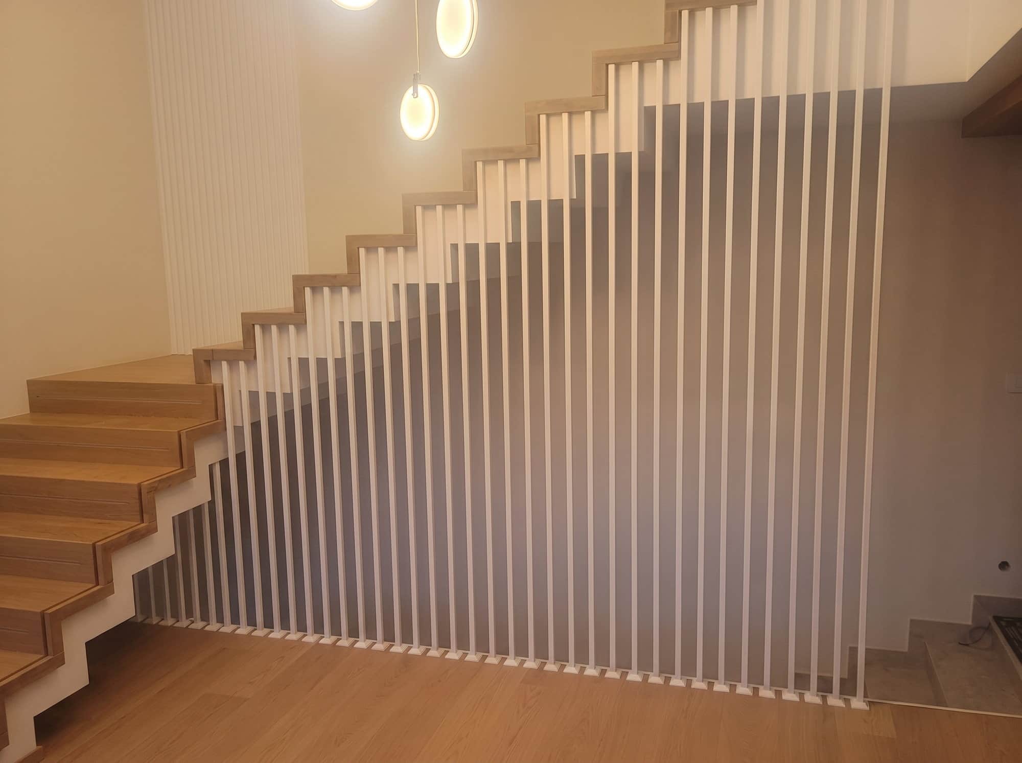 Balustrada z gęstych pionowych prętów wzdłuż schodów w jasnym wnętrzu