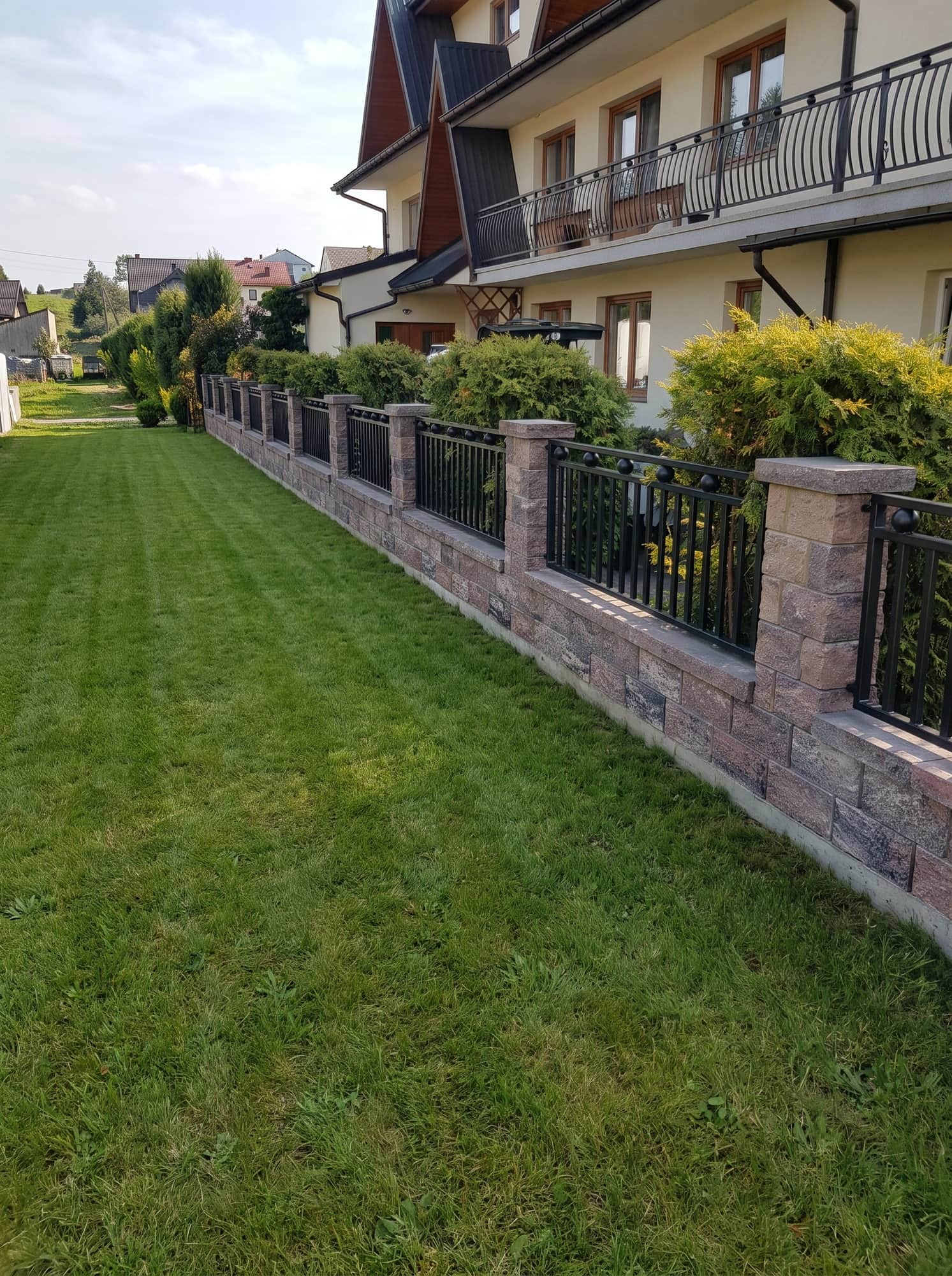 Ogrodzenie z przęseł stalowych biegnące wzdłuż domu i ogrodu